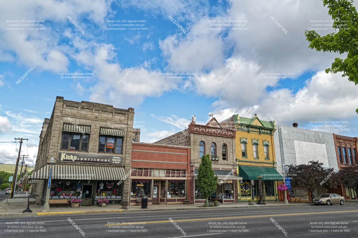 This image features a picturesque street scene showcasing historic buildings with colorful facades and inviting storefronts. The architecture hints at the town's rich history and vibrant local culture, capturing people shopping and strolling along the street.