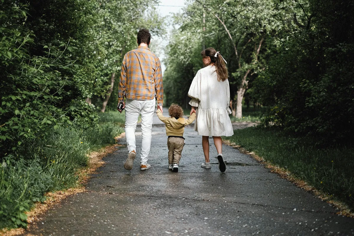 A family strolls along a winding pathway bordered by lush greenery, embodying the joy of nature exploration and togetherness. The setting is peaceful, emphasizing easy access to walking and cycling trails.