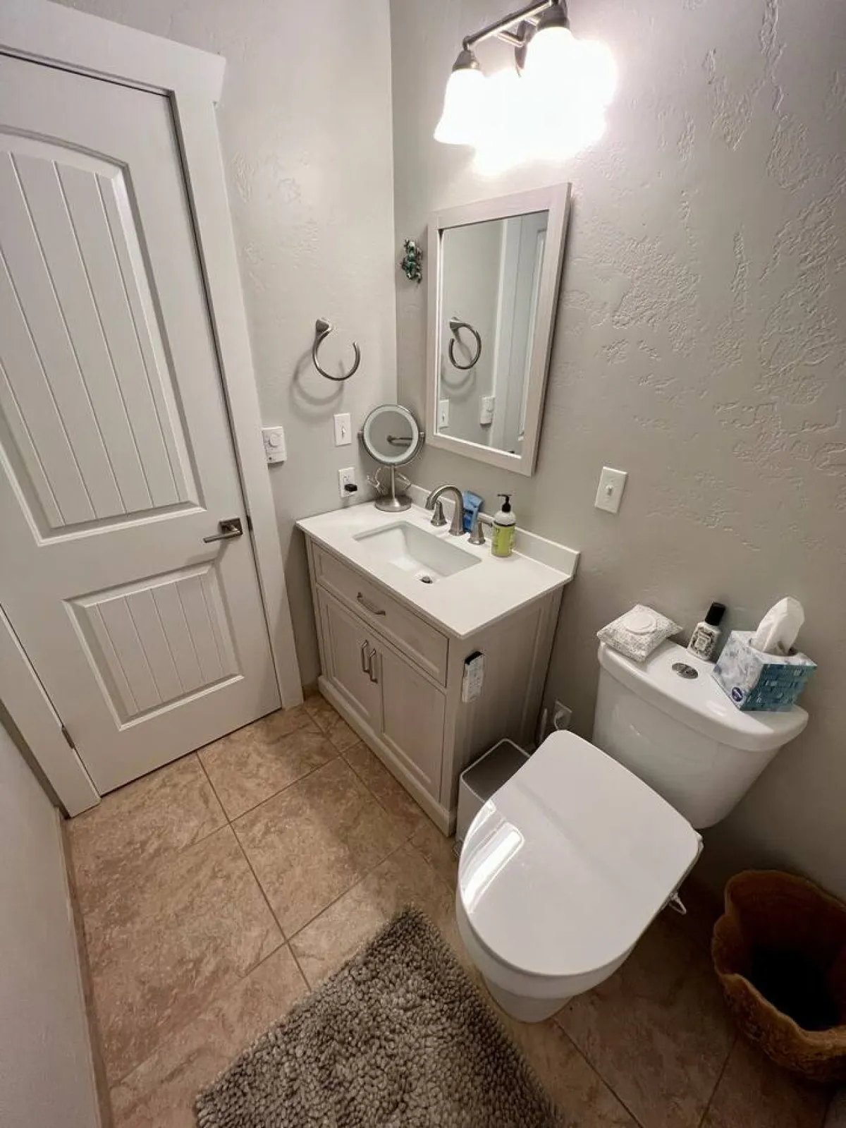 A calm, well-lit bathroom featuring a vanity with a sink, a mirror, a toilet, and modern light fixtures. The space feels refreshing and private, ideal for personal routines.